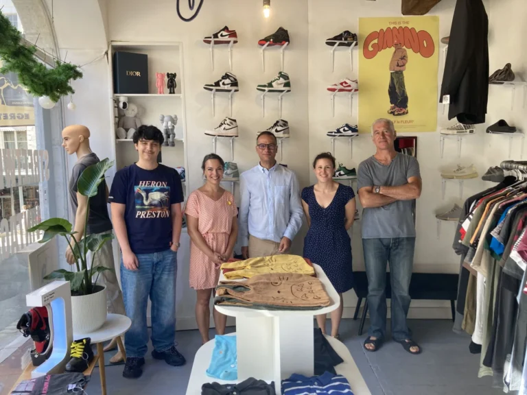 Cinq personnes debout dans la première boutique EGRETTA à Blois, devant un mur de sneakers et un portant de vêtements.