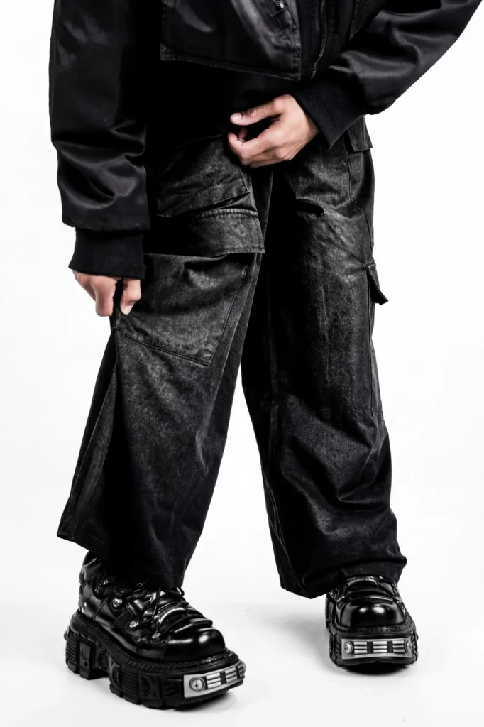 Gros plan sur un pantalon cargo noir délavé porté avec des chaussures noires à plateforme et plaques métalliques.